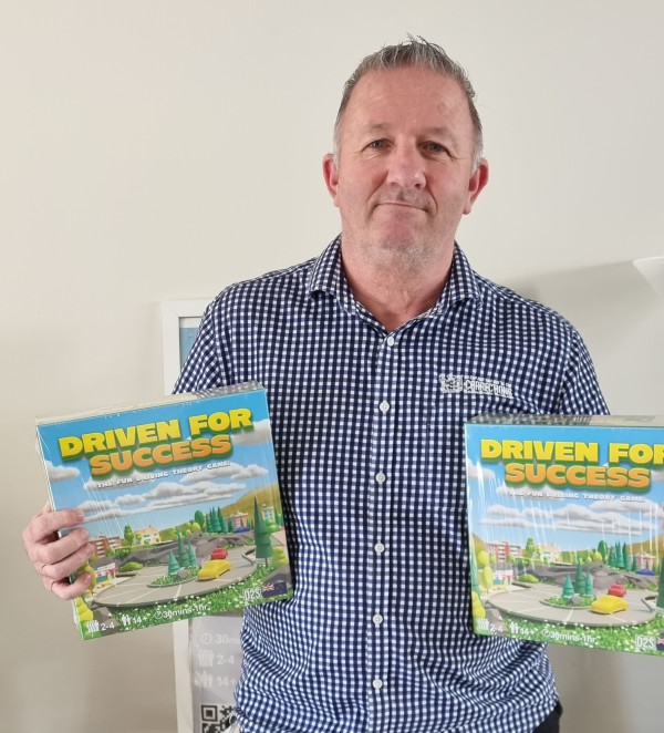 Ian holds up two the Driven for Success games, one in each hand
