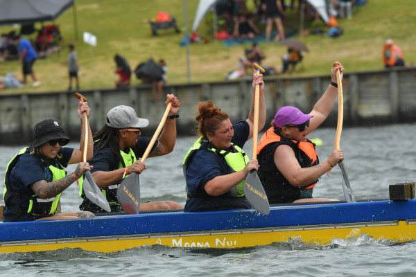Four Corrections staff paddle hard in a waka as part of the competition