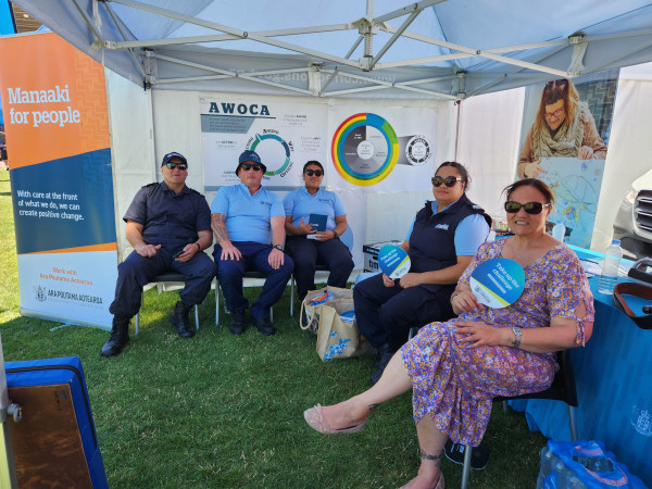 Corrections staff sit inside the marquee at the event, beside a banner that reads Manaaki for people